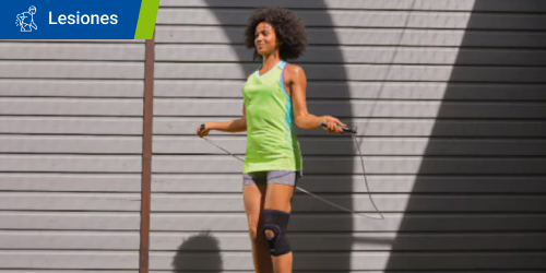 Mujer con ropa de ejercicio y un soporte para las rodillas utiliza una cuerda para saltar al aire libre. Mujer con ropa de ejercicio y un soporte para las rodillas utiliza una cuerda para saltar al aire libre.